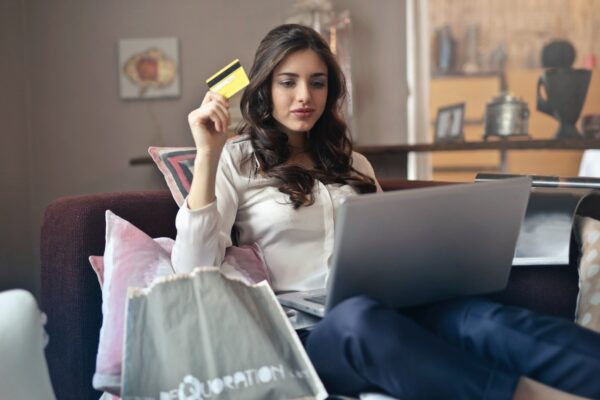 American Sales Tax for e-commerce entrepreneurs - woman with credit card in hand and laptop on her knee surrounded by shopping bags