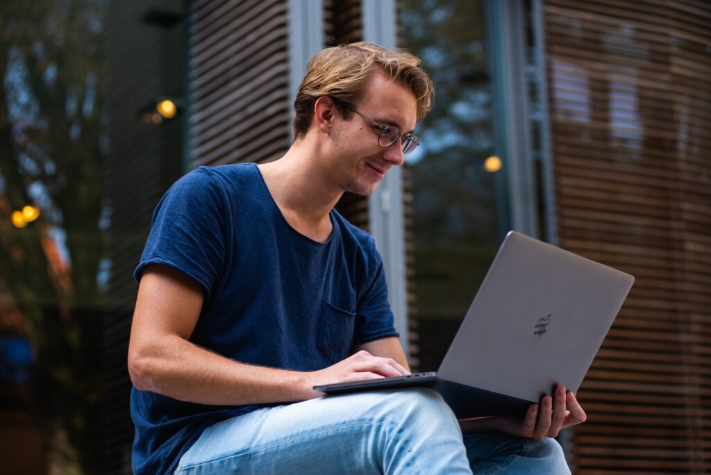 How do I become a limited company - man in blue tshirt sitting on a step using a laptop