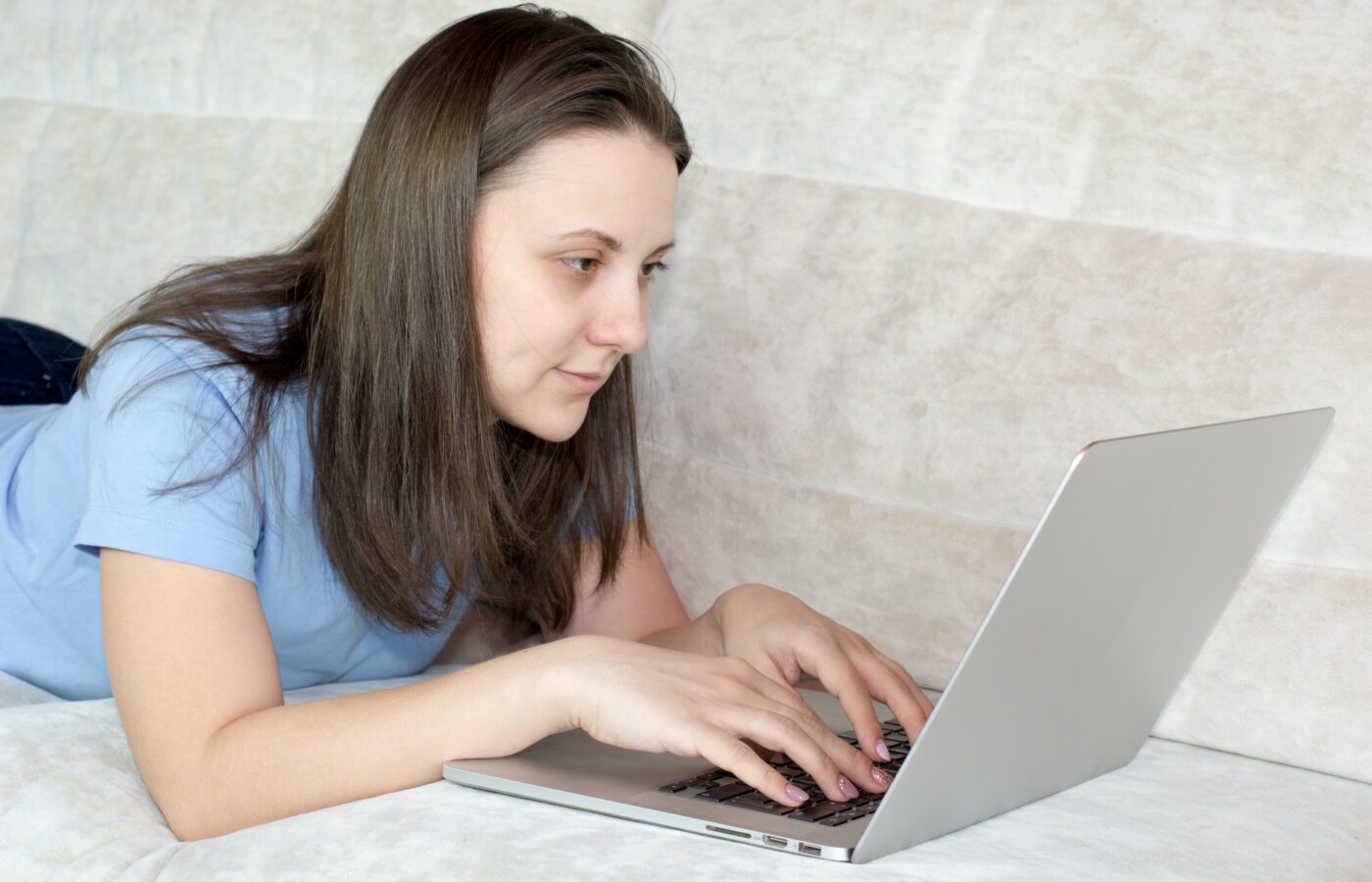 Do you pay VAT on eBay fees - lady in a blue tshirt working on a laptop lying on a bed