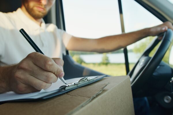 2021 VAT changes - man with arm on the wheel writing on a notepad on a delivery box