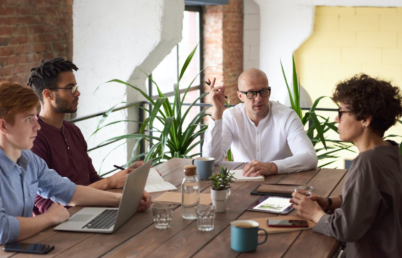 E-commerce due diligence - 4 people sitting at a large wooden table holding a business meeting