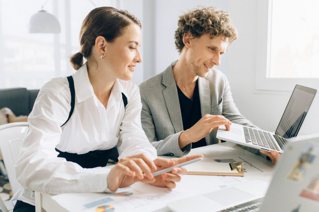 Square vs Stripe - man in agrey suit jacket and black tshirt with a woman in a white shirt and ponytail looking at a laptop at a white minimalist desk