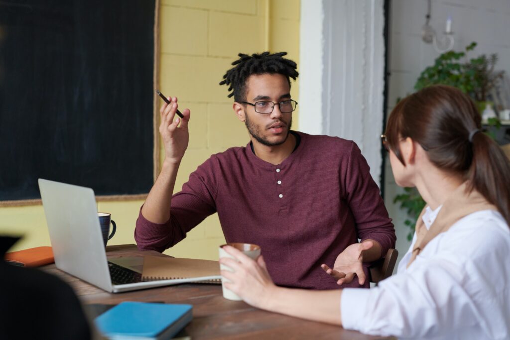 What is Companies House e-commerce - man in a burgundy henley shirt with a pen raised, sitting at a desk with a woman in a white shirt