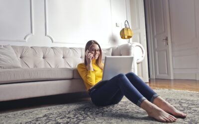 Can you use a credit card to pay HMRC - lady sitting on floor resting back on sofa with laptop on lap yellow poloneck and jeans