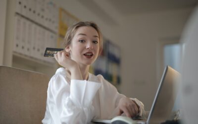 paypal fees and alternatives - woman dressed in white sitting at a laptop holding a credit card