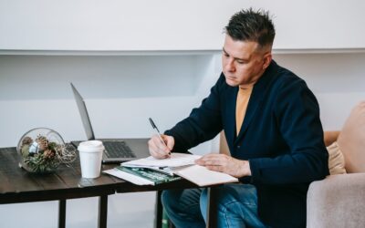 Amazon VAT UK Changes - Man writing in a notebook on a desk with a laptop and coffee