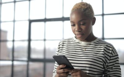 Notify my accountant - woman in a stripey top in front of a window looking at her phone
