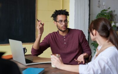 What is Companies House e-commerce - man in a burgundy henley shirt with a pen raised, sitting at a desk with a woman in a white shirt