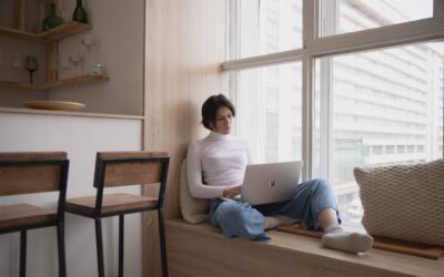 What is Xero Analytics Plus - woman in a white polo neck and jeans with short dark hard working in a window seat on a laptop